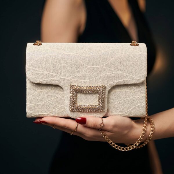 Sac à main en cuir beige avec boucle en strass, accessoire élégant pour occasions spéciales..