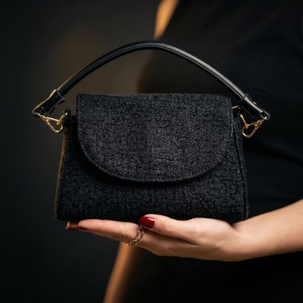 Sac à main en tissu noir avec poignée en cuir, style chic et sophistiqué..